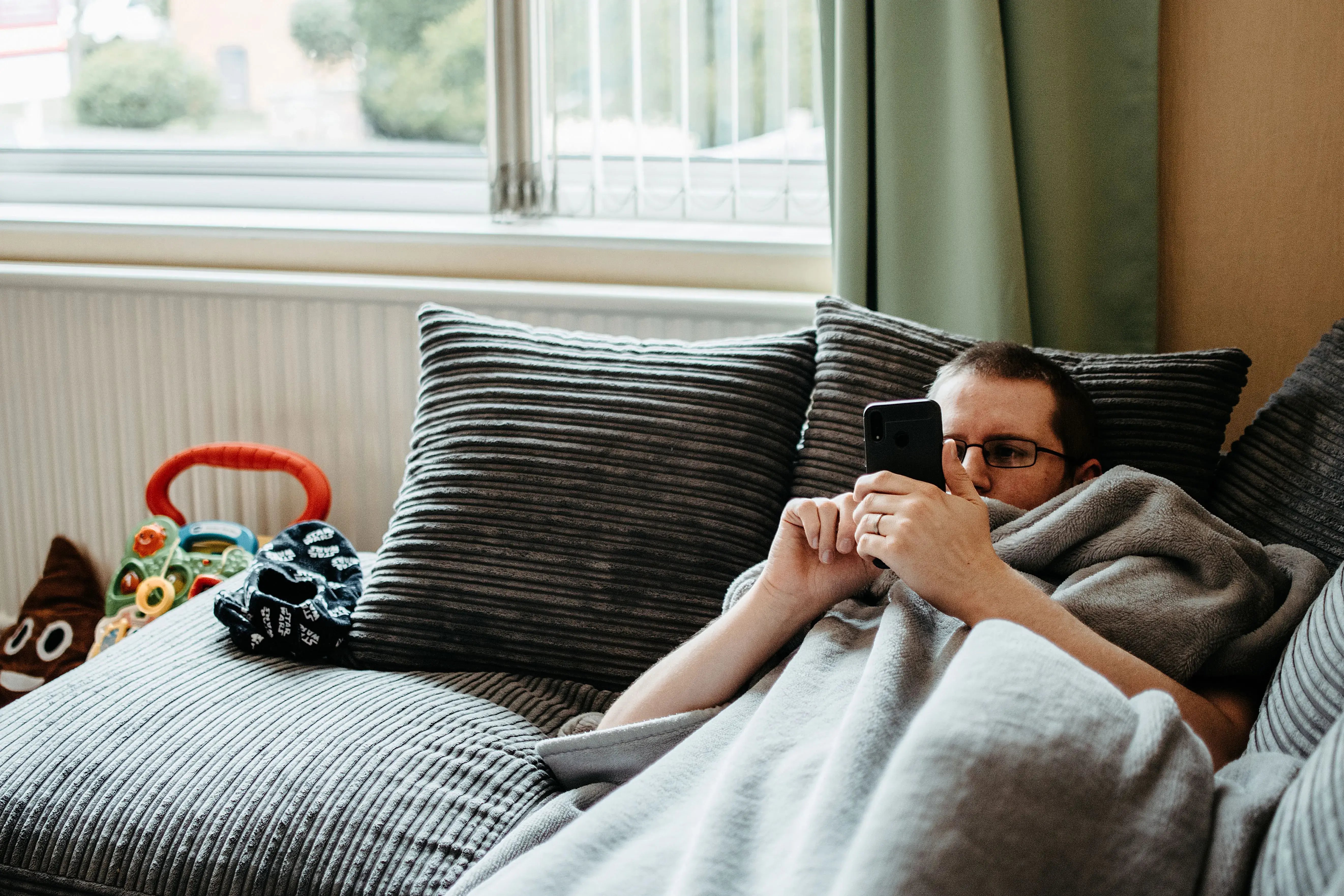 man scrolling on phone laying down