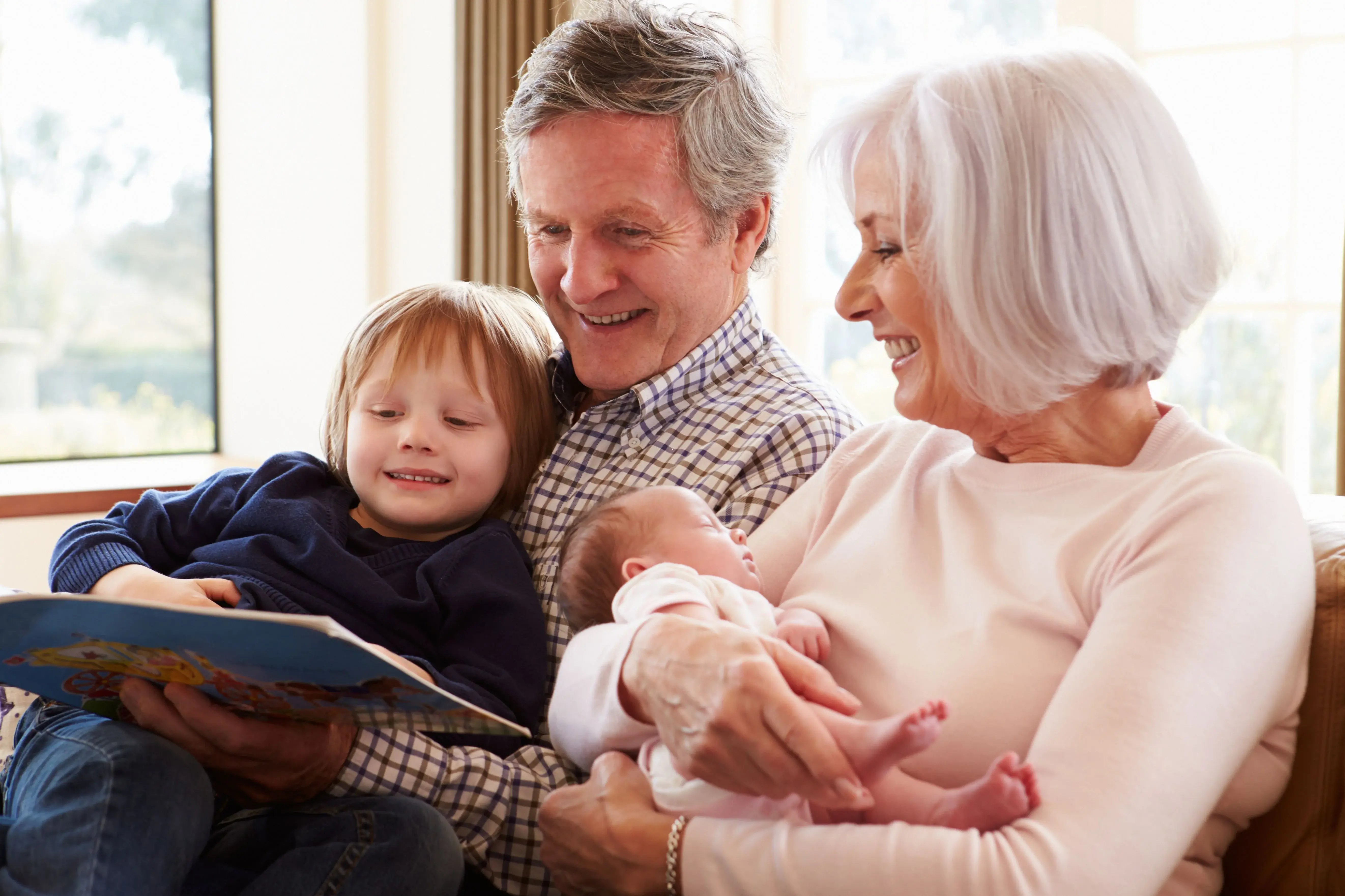 grandparents with young children reading book