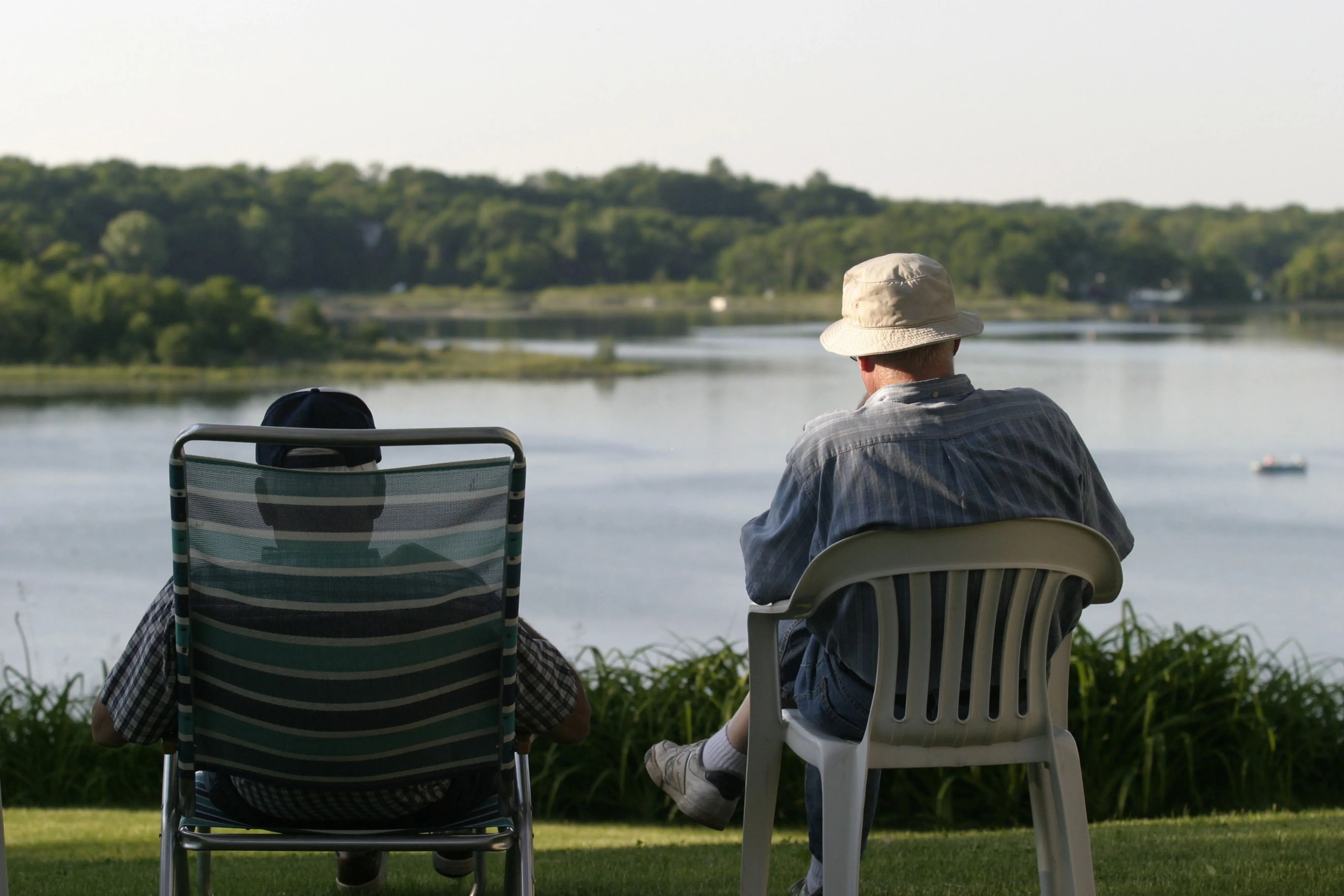 2 older men relaxing next to the lake