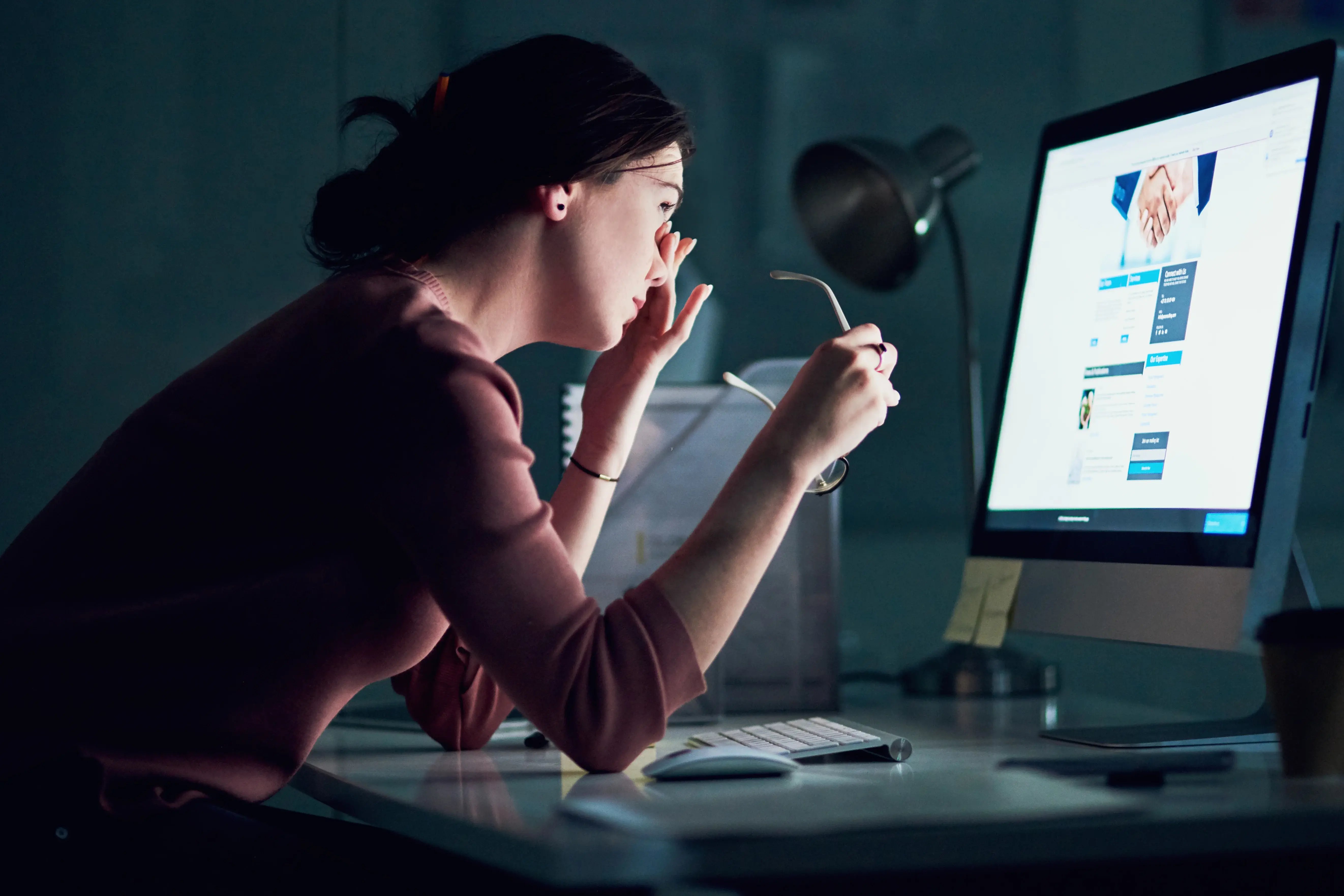 woman rubbing eyes at desk