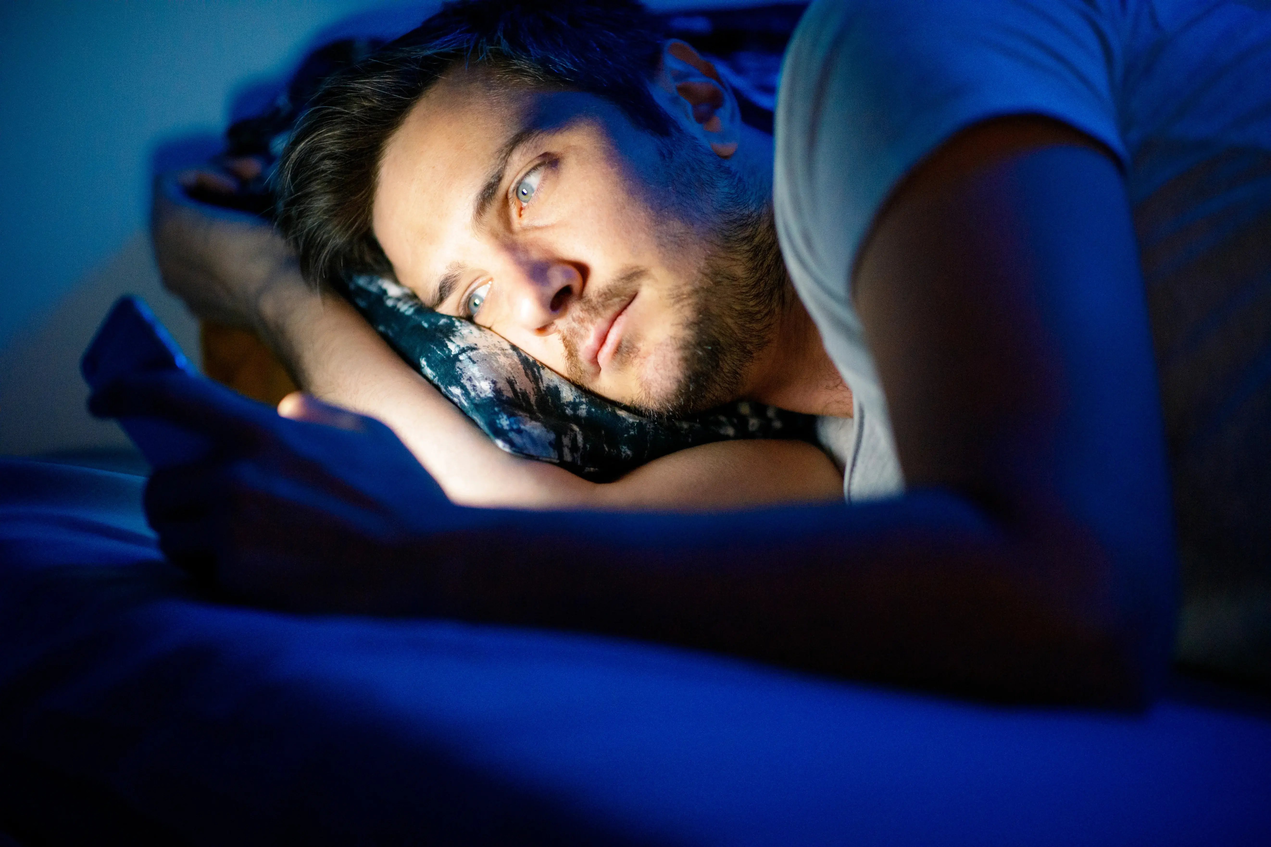 man looking at phone in bed